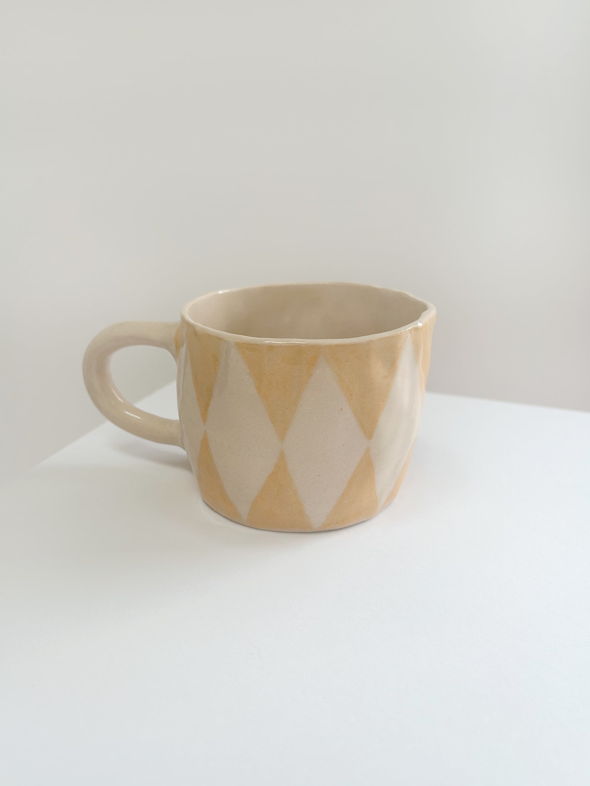 yellow mug with diamond pattern on a white surface
