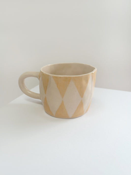 yellow mug with diamond pattern on a white surface